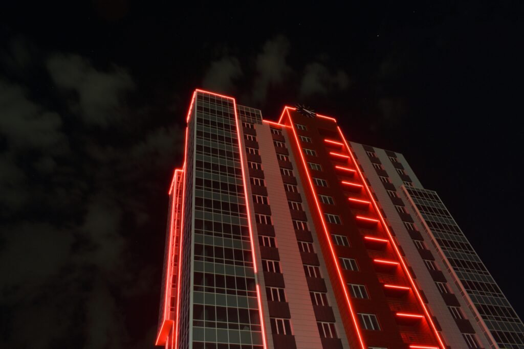 A striking view of a skyscraper with red neon lights against a night sky.