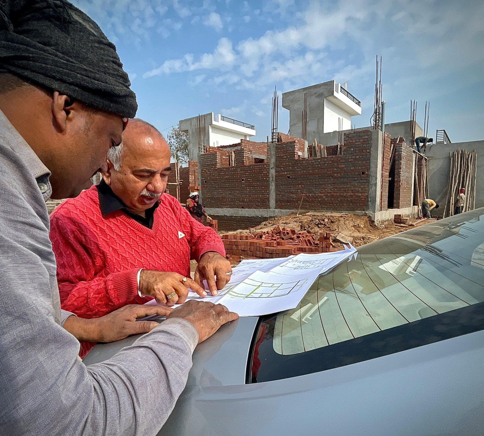 Team of architects examining building plans outdoors at a construction site.